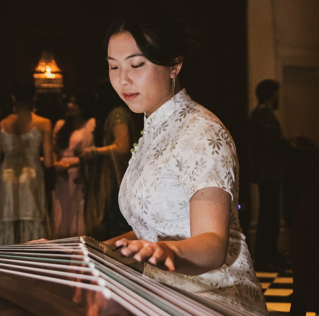 A woman in a white dress playing a musical instrument