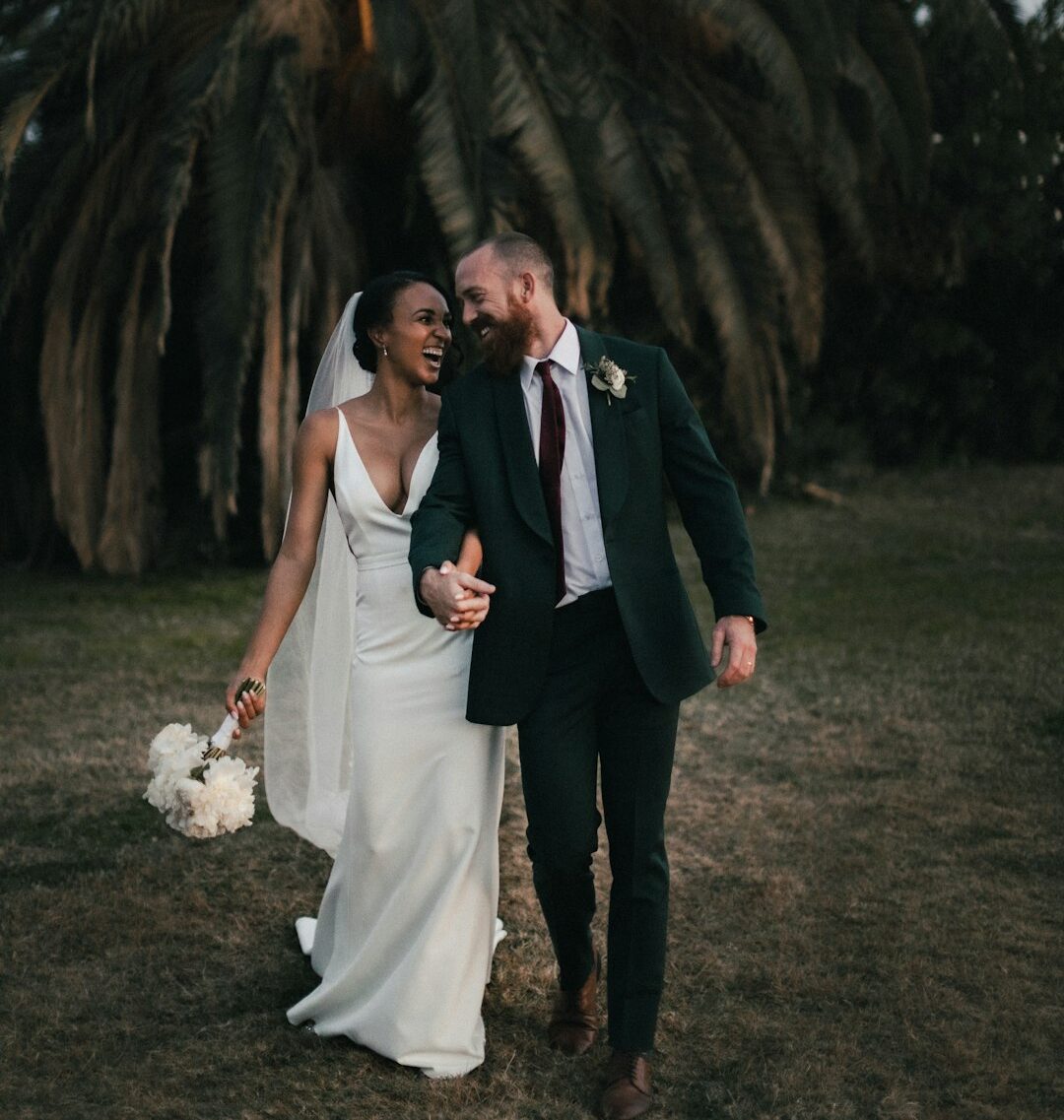 a newly married couple walking through a field